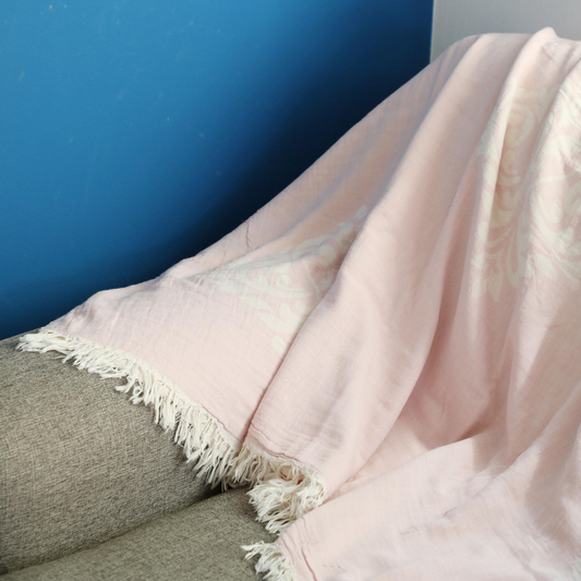 Powder-pink, cotton Turkish throw/blanket has baroque designs on it