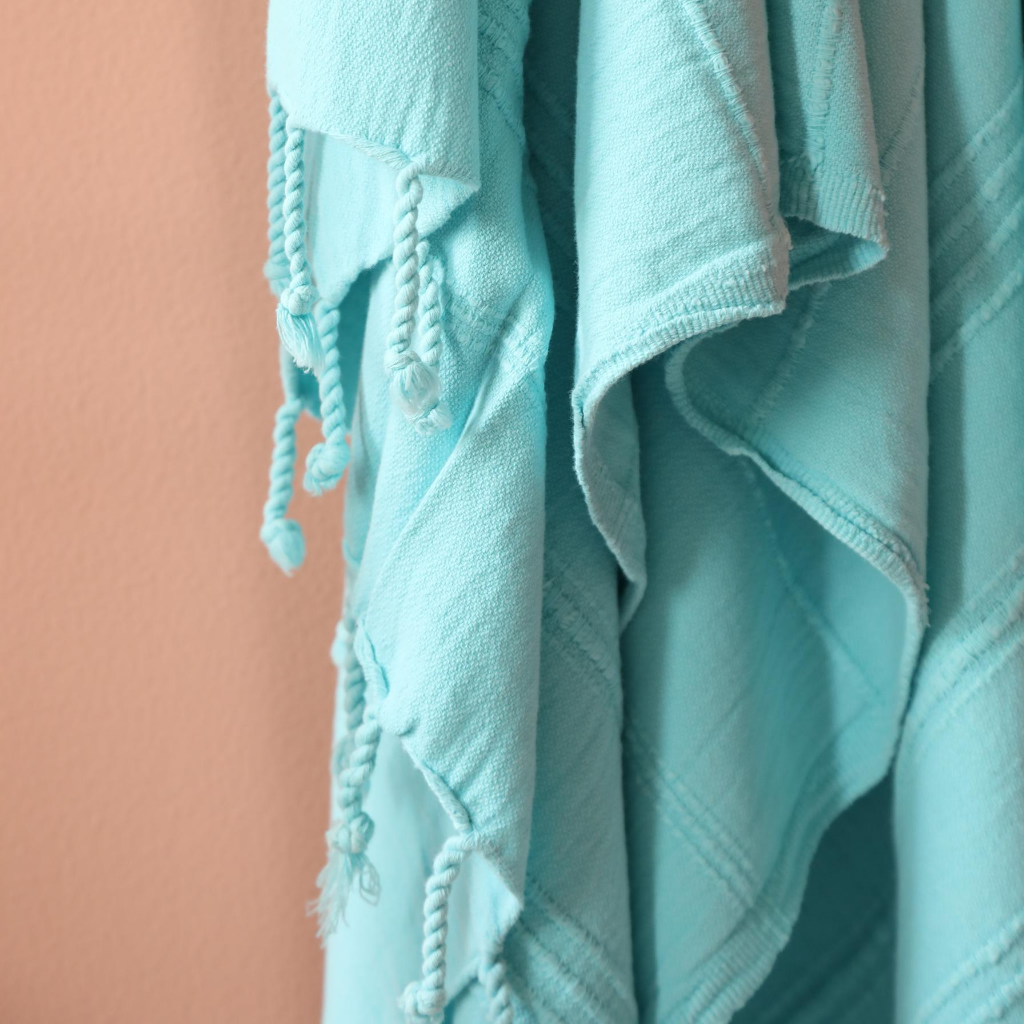 Soft, turquoise color Turkish beach/bath towel has hand-tied tassels