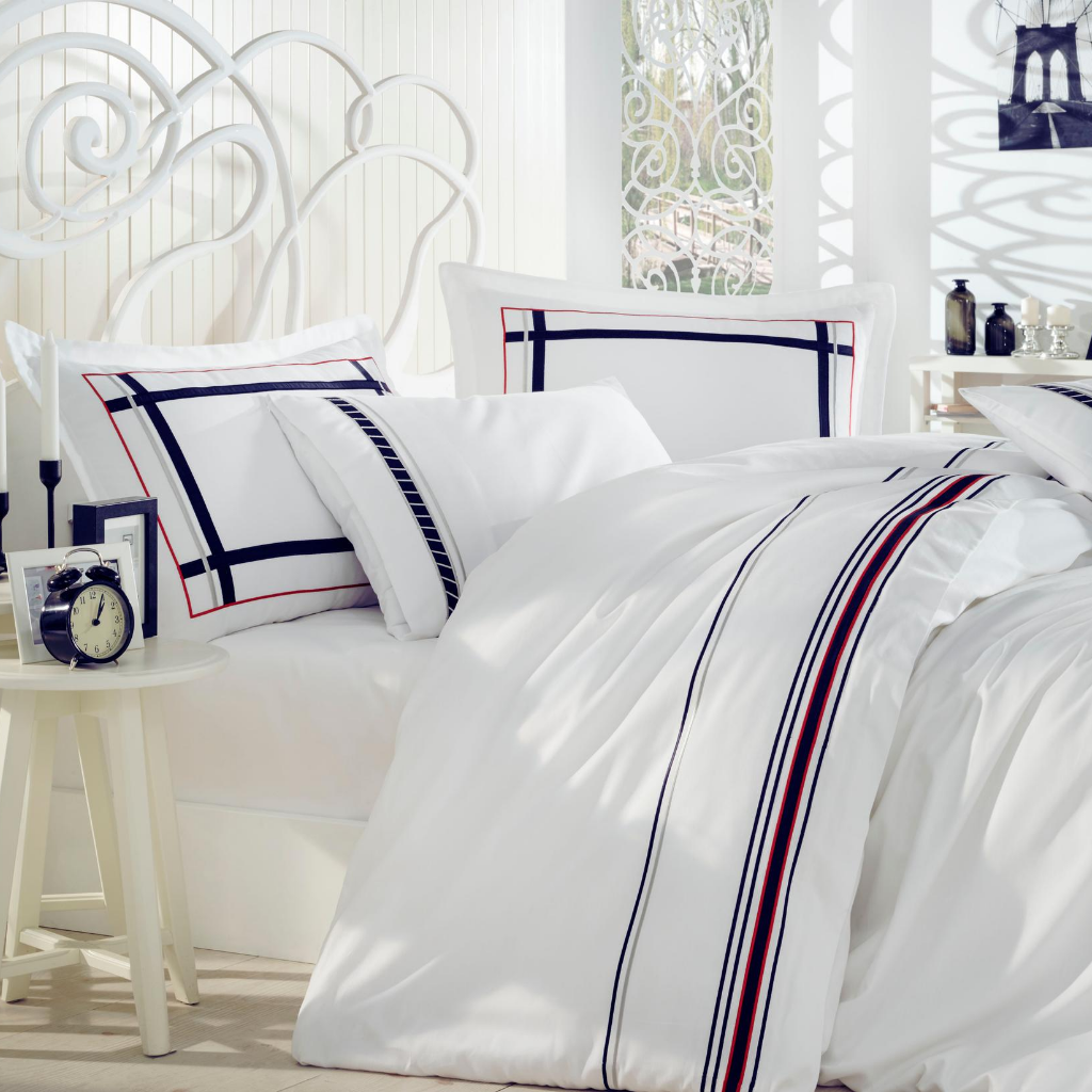 Minimalist bedroom decorated with white bed linen set which has navy and red lines at borders